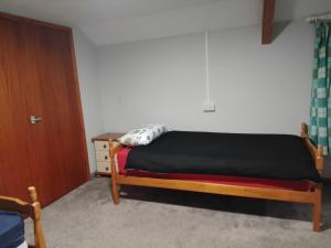 1 dormitorio con 1 cama, vestidor y puerta en Dolphins Backpackers, en Tintagel