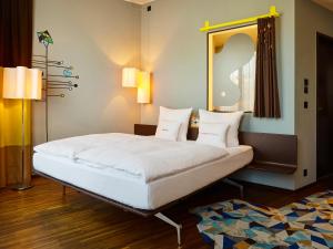 a bedroom with a large white bed with a mirror at 25hours Hotel Zürich West in Zurich