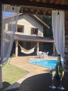 uma mesa com dois copos de vinho ao lado de uma piscina em Sítio dos Coqueiros, em meio a natureza com piscina em Carlos Barbosa