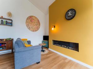 Charming holiday home in Kaatsheuvel with hot tub في كاتْسهوفيل: غرفة معيشة بها أريكة زرقاء وساعة على جدار أصفر