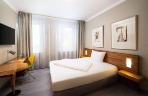 ハノーファーにあるelaya hotel hannover cityのベッドとデスクが備わるホテルルームです。