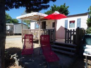 weranda z czerwonymi krzesłami i parasolem w obiekcie Mobil Home Les salins de la gardiole w mieście Vic-la-Gardiole