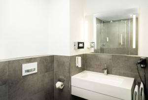 a bathroom with a white sink and a mirror at elaya hotel hannover city in Hannover