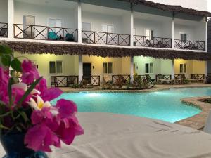 um hotel com piscina e flores roxas em Kibanda Lodge and Beach Club em Nungwi