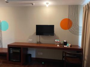 Habitación con escritorio y TV en la pared. en Stay G Service Residence Jatibening en Kaliastana