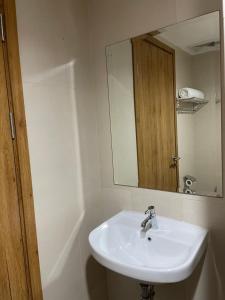 La salle de bains est pourvue d'un lavabo blanc et d'un miroir. dans l'établissement Stay G Service Residence Jatibening, à Kaliastana