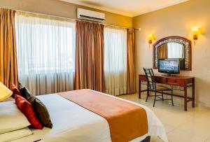 a hotel room with a bed and a desk with a television at Bulawayo Rainbow Hotel in Bulawayo