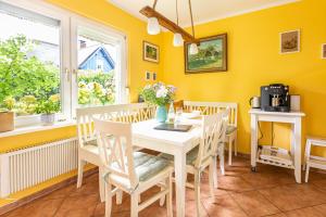 ein Esszimmer mit gelben Wänden, einem weißen Tisch und Stühlen in der Unterkunft Ferienhaus Ankerherz in Wustrow