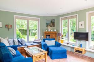 sala de estar con sillas azules y TV en Ferienhaus Ankerherz, en Wustrow