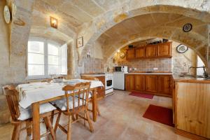 una cocina con mesa y una gran pared de piedra. en Tal-Barun Farmhouse, en San Lawrenz