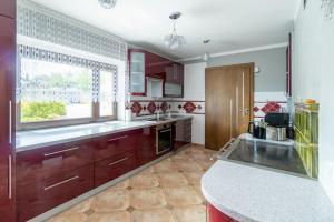 a kitchen with red cabinets and a large window at Słoneczny dom w górach, Sauna, basen Karpacz Opawa in Lubawka