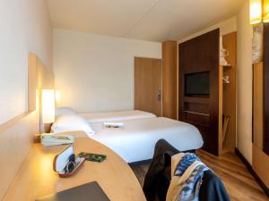 een hotelkamer met een wit bed en een bureau bij Hotel Ibis Antwerpen Centrum in Antwerpen