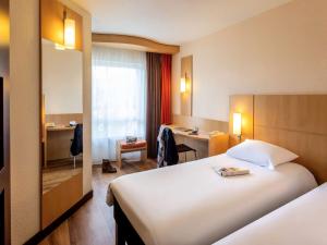 a hotel room with a large bed and a desk at ibis Antwerpen Centrum in Antwerp