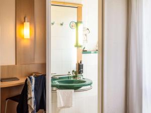 un bagno con un lavandino verde e uno specchio di ibis Antwerpen Centrum ad Anversa