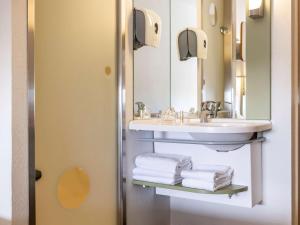 a bathroom with a sink and a mirror and towels at ibis budget Antwerpen Centraal Station in Antwerp