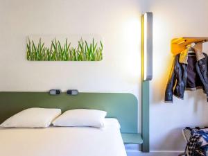 een slaapkamer met een bed met een groen hoofdeinde en gras aan de muur bij ibis budget Antwerpen Centraal Station in Antwerpen