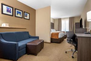 Habitación de hotel con sofá azul y cama en Comfort Suites Mobile West/Tillmans Corner, en Mobile