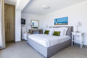 - une chambre dotée d'un grand lit avec des draps blancs et des oreillers verts dans l'établissement Villa Antigone Luxury Retreat, à Skopelos