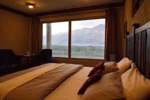 Bett in einem Zimmer mit einem großen Fenster in der Unterkunft Baltistan Fort in Skardu