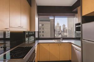 a kitchen with a view of the city from a window at Adina Apartment Hotel Melbourne in Melbourne