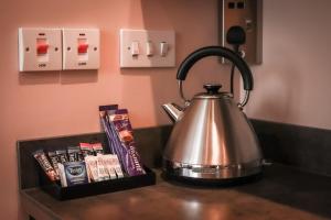 a tea kettle on a counter next to a box of books at Nort Bode Apartments in Lerwick