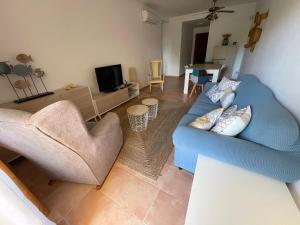 a living room with a blue couch and two chairs at Luminoso y tranquilo apartamento con jardin en campo de Golf Valle del Este in Vera