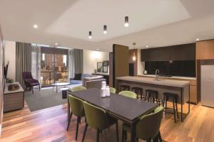 a kitchen and living room with a table and chairs at Adina Apartment Hotel Melbourne in Melbourne