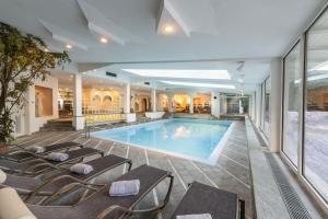 ein Pool in einem Hotel mit Liegestühlen um ihn herum in der Unterkunft Ferien & Wellnesshotel Windschar in Bruneck