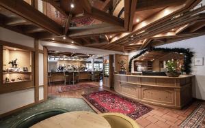a large room with a bar with tables and rugs at Ferien & Wellnesshotel Windschar in Brunico