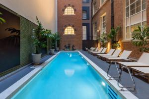 uma piscina num hotel com cadeiras e mesas em Adina Apartment Hotel Brisbane em Brisbane