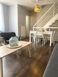 uma sala de estar com uma mesa e cadeiras e uma escadaria em Malo les bains: duplex à deux pas de la plage. em Dunkerque