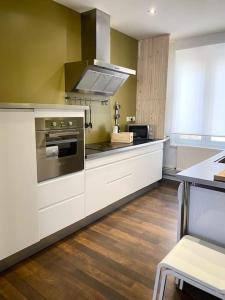 uma cozinha com armários brancos e um forno com placa de fogão em Malo les bains: duplex à deux pas de la plage. em Dunkerque
