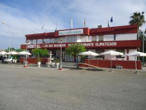 ein rotweißes Gebäude mit weißen Sonnenschirmen in der Unterkunft Hostal los Dos Naranjos in El Arahal