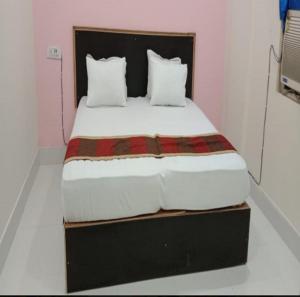1 cama con sábanas blancas y almohadas en una habitación en Hotel Indraprastha By WB Inn, en Alwar