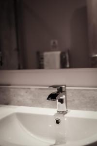 a bathroom sink with a faucet in front of a mirror at Nort Bode Apartments in Lerwick