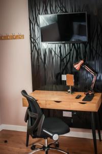 a desk with a chair and a television on a wall at Nort Bode Apartments in Lerwick