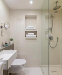 een badkamer met een douche, een toilet en een wastafel bij H10 London Waterloo in Londen