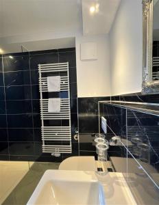 a bathroom with a sink and a black tiled wall at Hotel Wasserschloss Mellenthin in Mellenthin