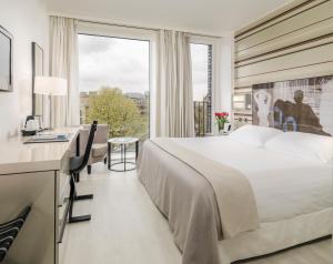 Habitación de hotel con cama, escritorio y ventana en H10 London Waterloo en Londres