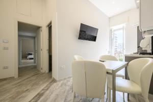 a white dining room with a table and chairs at [LUNGOMARE 6min] Suite Deluxe Miraglia with Parking in Naples
