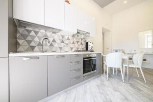 a kitchen with white cabinets and a table with white chairs at [LUNGOMARE 6min] Suite Deluxe Miraglia with Parking in Naples