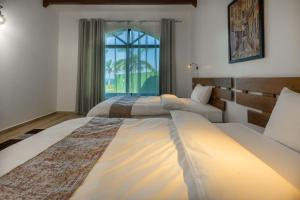 two beds in a room with a window at Aya Sophia Villa Garden Hotel in Dar es Salaam