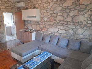 ein Wohnzimmer mit einem Sofa und einer Steinmauer in der Unterkunft Kamena Kuca Family Rodin in Čapljina