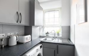 uma cozinha branca com um lavatório e uma janela em Stunning and Spacious 4 Bed Apr next to BrickLane em Londres