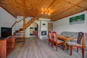 a living room with a wooden table and chairs and a staircase at Zajazd pod Sosnami in Berezka