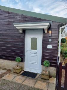 a house with a white door and two plants at The Chalet in Radstock