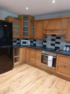 a kitchen with wooden cabinets and a black appliances at The Chalet in Radstock