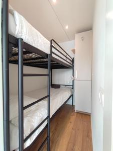 two bunk beds in a room with a refrigerator at Blue Mind, heerlijk vakantiehuisje op het water: in Vinkeveen