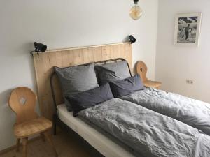a bedroom with a bed with a wooden headboard and a chair at Herberge. 46 in Garmisch-Partenkirchen