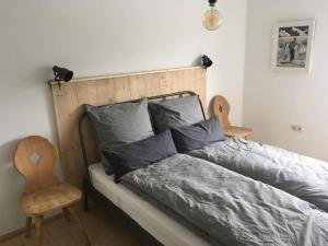 Schlafzimmer mit einem Bett mit einem Kopfteil aus Holz und einem Stuhl in der Unterkunft Herberge. 46 in Garmisch-Partenkirchen